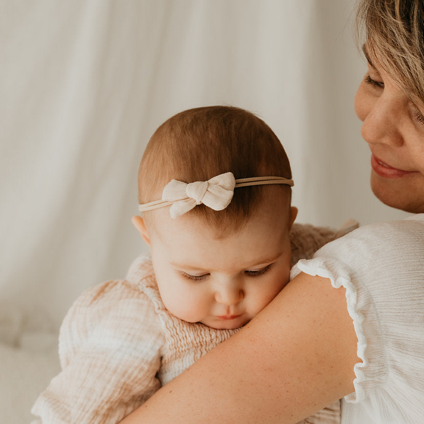 Baby mit Haarschleife auf dem Arm der Mutter