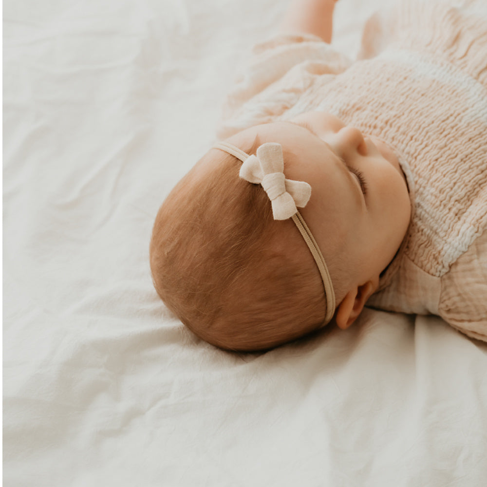 Baby mit kleiner Haarschleife in beige