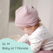 Baby mit Beanie aus weicher Baumwolle mit feinem Lochmuster in hellrosa