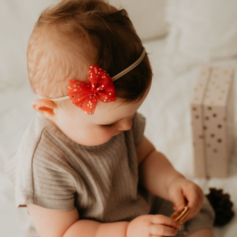 Baby mit roter Haarschleife aus Tüll an Haarband