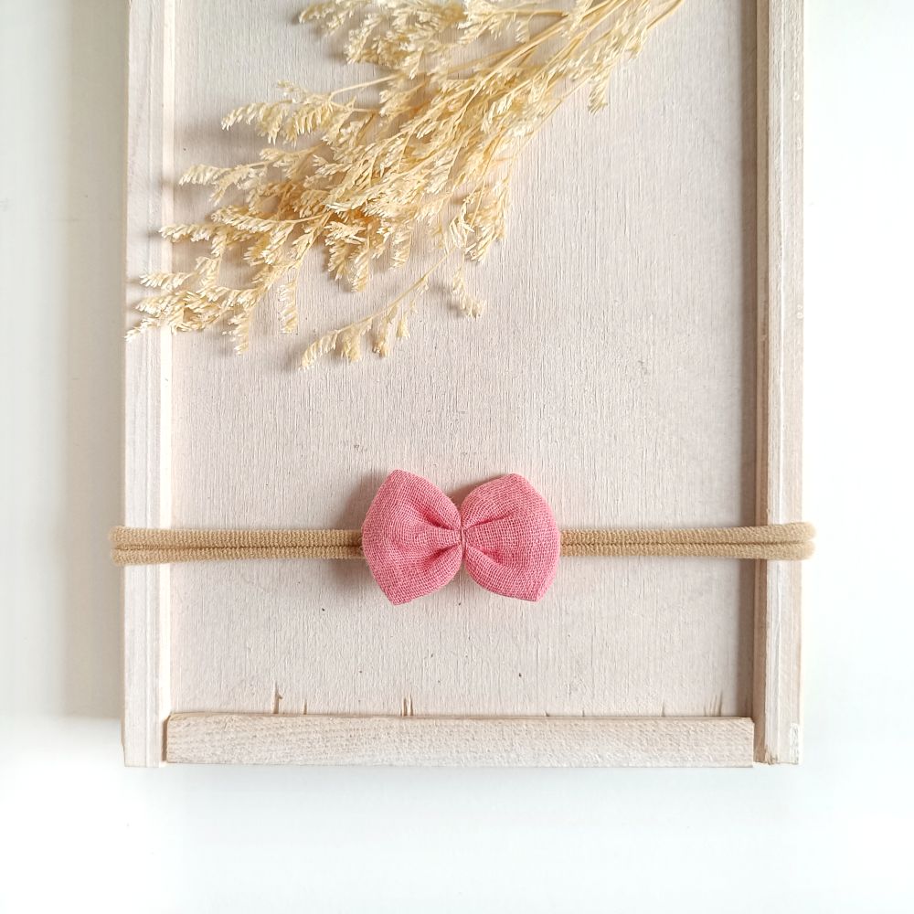 kleine Haarschleife für Babys aus Musselin in pinkrose an einem elastischen Haarband
