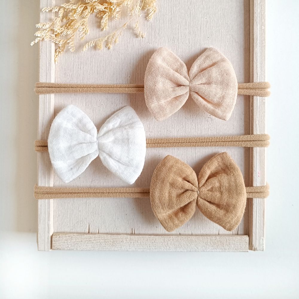 Haarschleifen für Babys in den Farben weiß, sand und beige aus musselin an einem elastischen Haarband