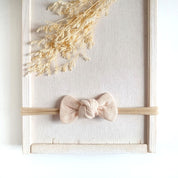 Baby mit kleiner Haarschleife in beige aus Musselin an einem elastischen Haarband