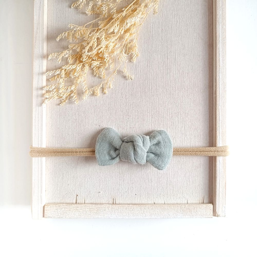 Baby mit kleiner Haarschleife in mint aus Musselin an einem elastischen Haarband