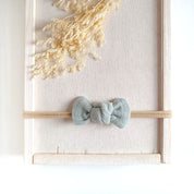 Baby mit kleiner Haarschleife in mint aus Musselin an einem elastischen Haarband