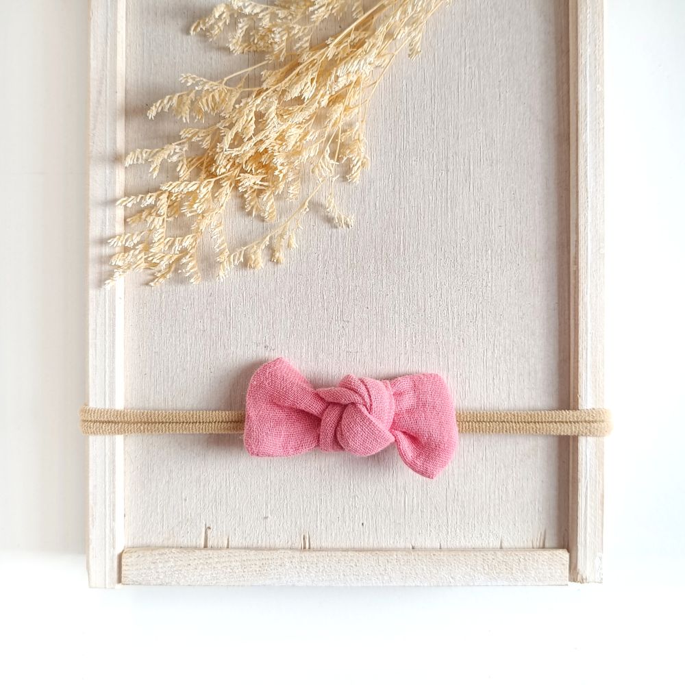 Baby mit kleiner Haarschleife in zartem Pink aus Musselin an einem elastischen Haarband