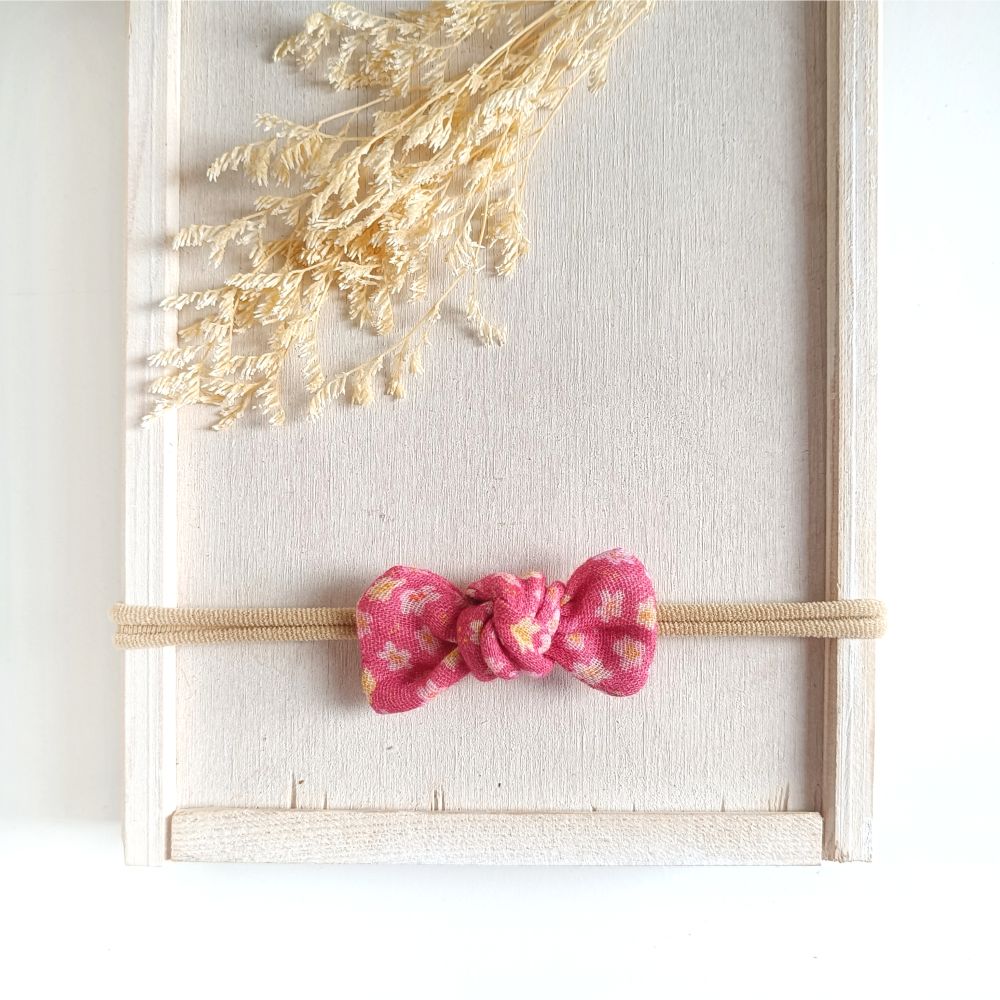 Baby mit kleiner Haarschleife rosa mit Blümchen aus Musselin an einem elastischen Haarband