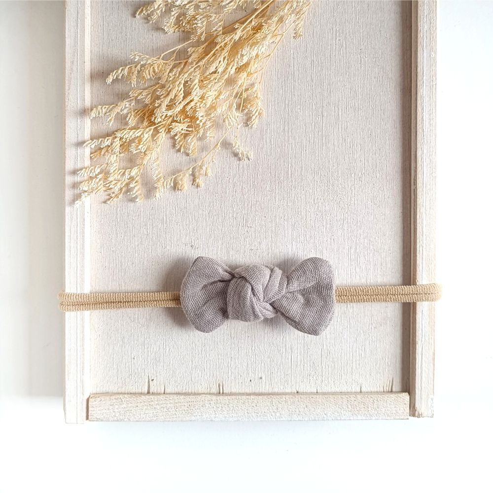 kleine Haarschleife in taupe aus Musselin an einem elastischen Haarband