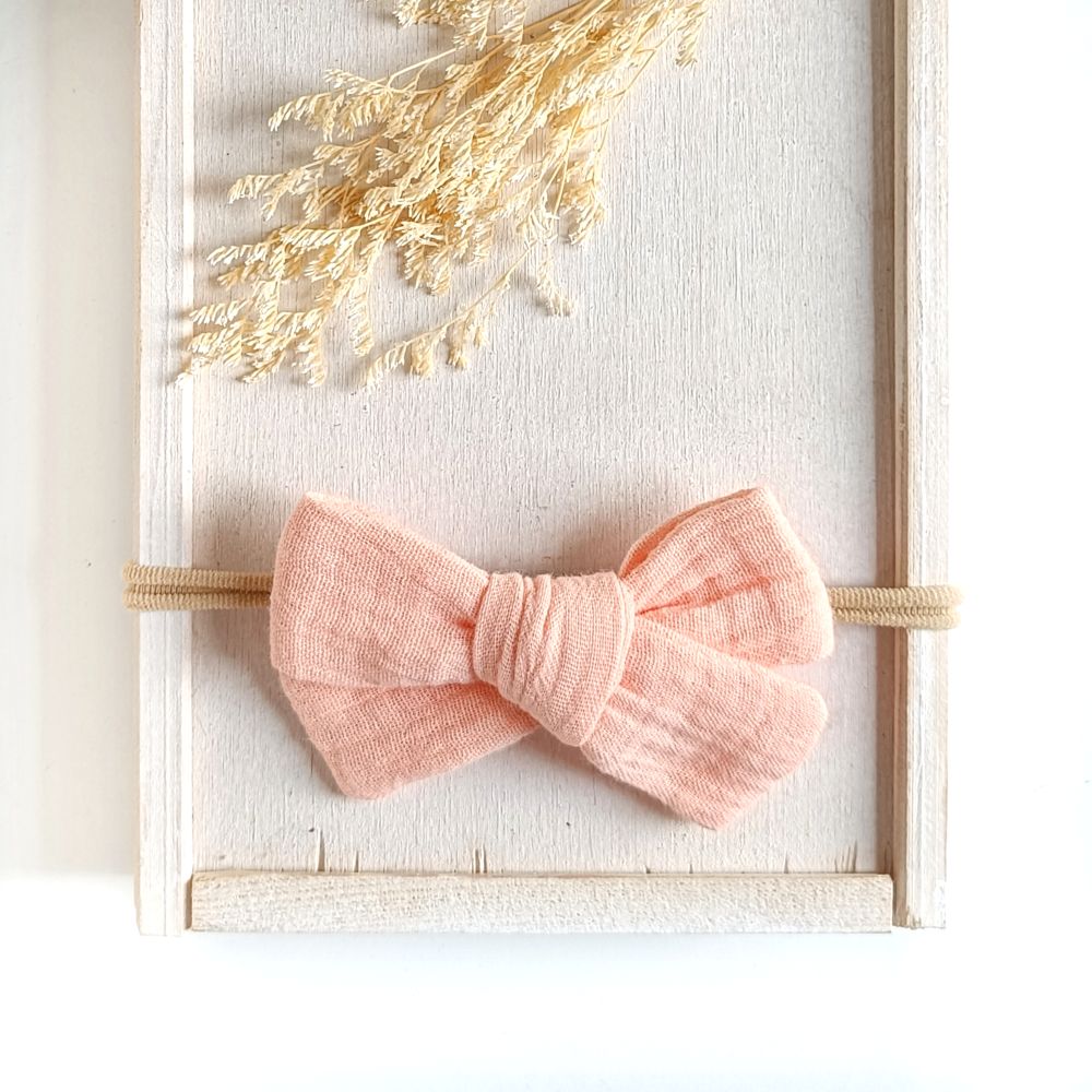 große Haarschleife für Babys aus Musselin in nude an einem elastischen Haarband