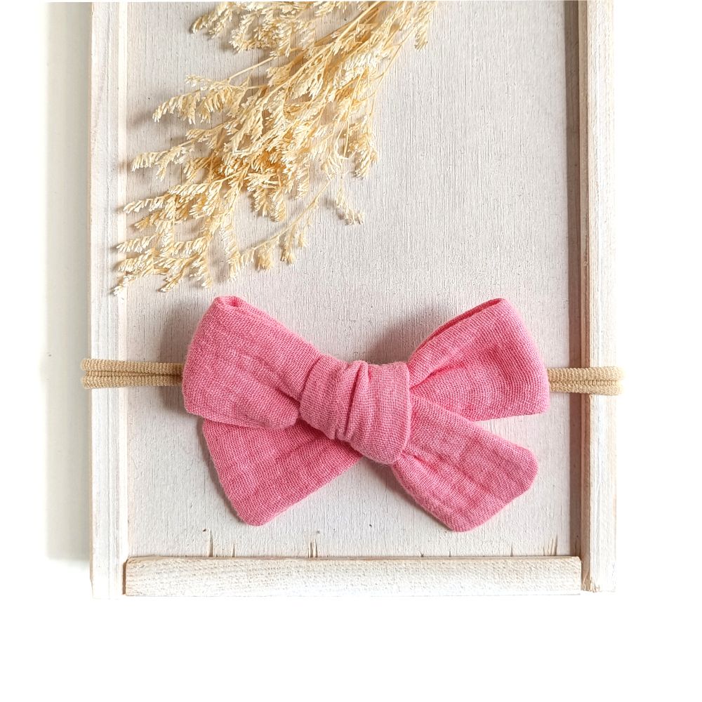 große Haarschleife für Babys aus Musselin in zartem Pink an einem elastischen Haarband