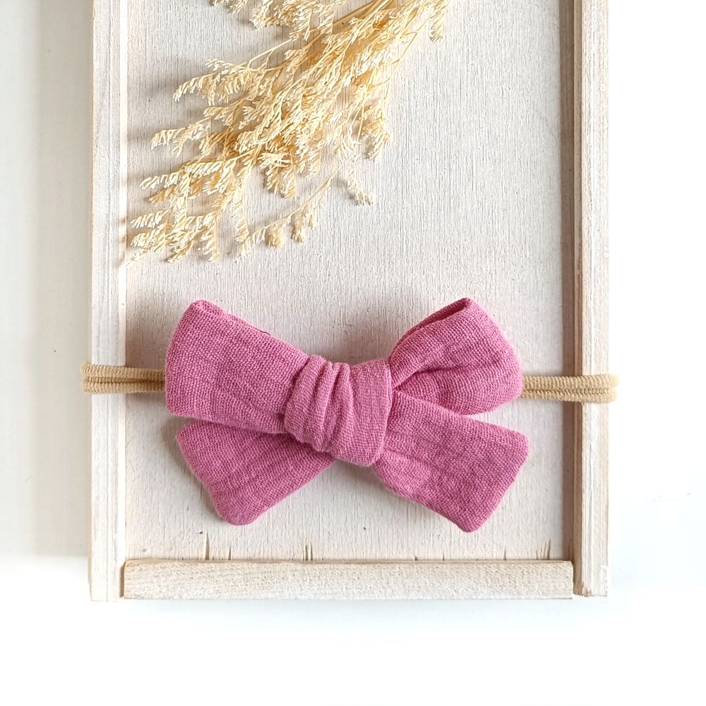 große Haarschleife für Babys aus Musselin in rosa an einem elastischen Haarband