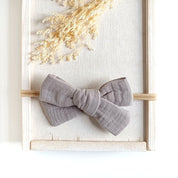 große Haarschleife für Babys aus Musselin in taupe an einem elastischen Haarband