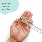 kleine Haarschleife aus Musselin für Babys in der Farbe sand an einem Haarband Detailbild