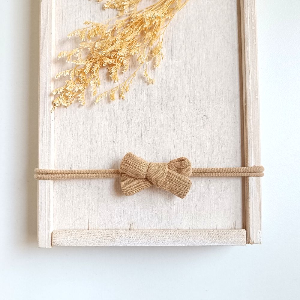 kleine Haarschleife für Babys aus Musselin in der Farbe sand an einem elastischen Haarband