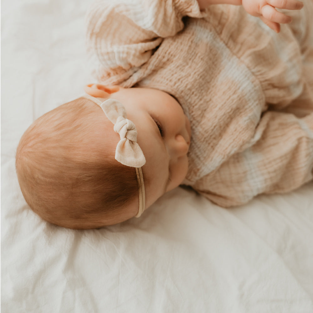Baby mit Haarschleife in beige