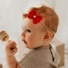 Baby mit roter Haarschleife an Haarband