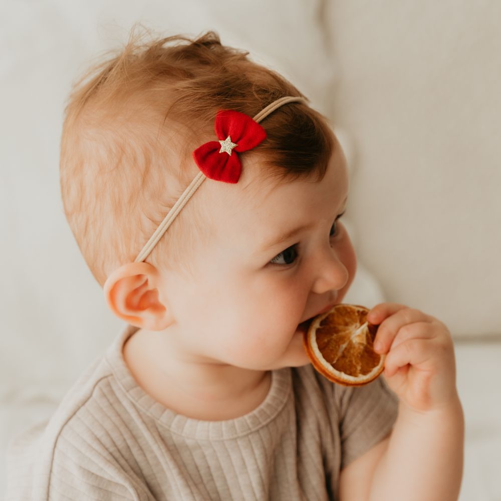 Baby mit kleiner roten Schleife an Haarband