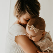 Baby mit Haarschleife auf dem Arm der Mutter